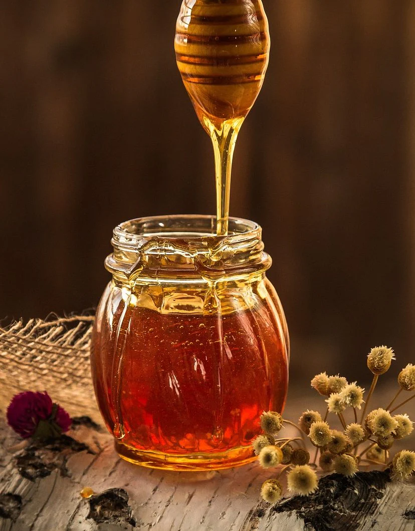Raw honey falling in a ribbon from a wooden dipper